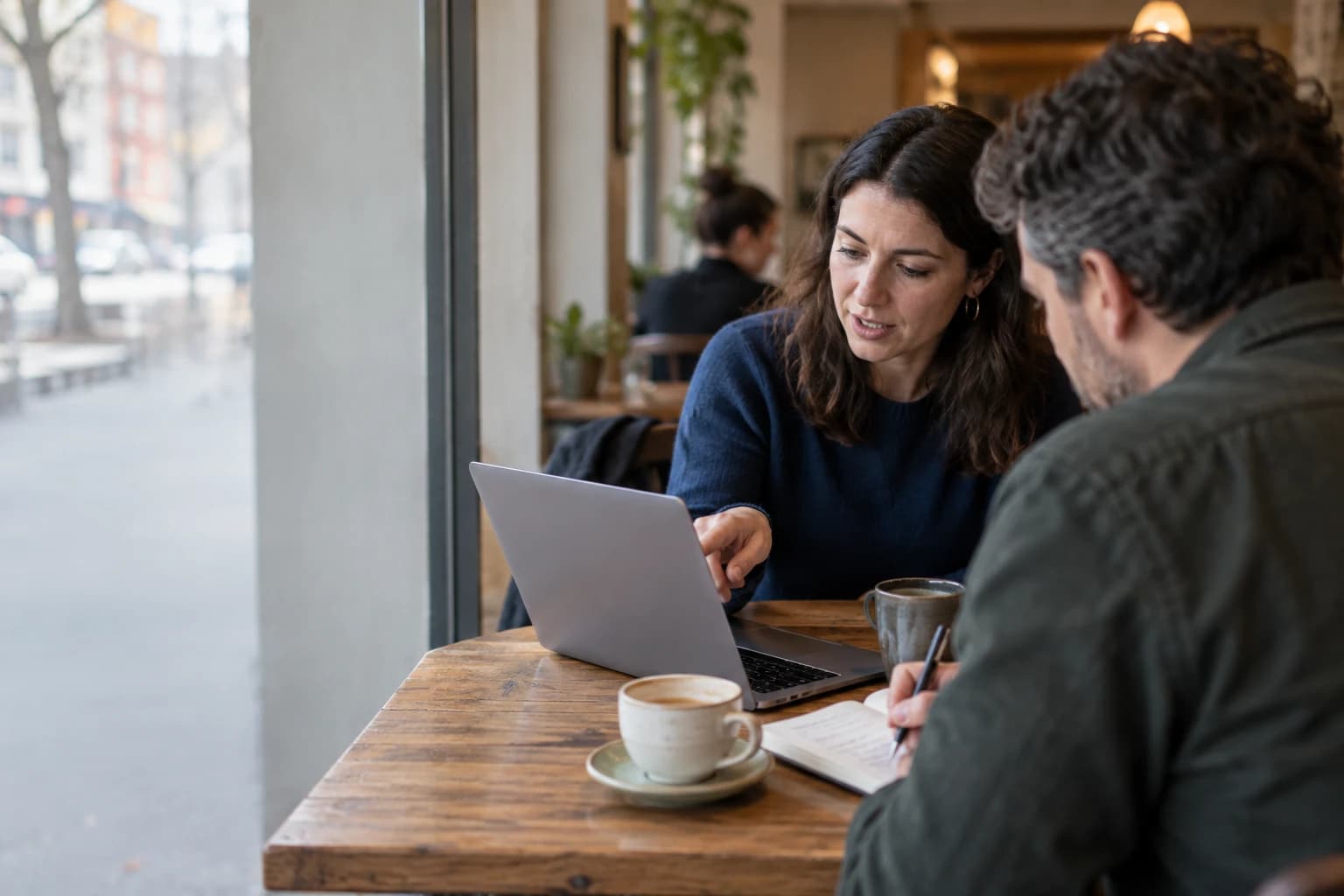 Two people reviewing a laptop together at a café table